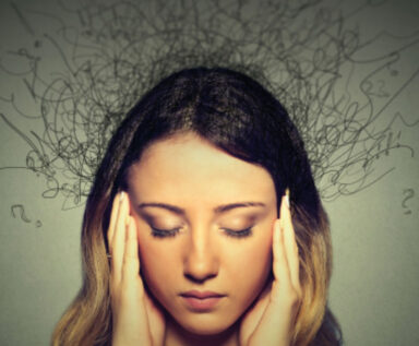 Young woman with eyes closed, rubbing her temples with an illustration of scribbles above her head