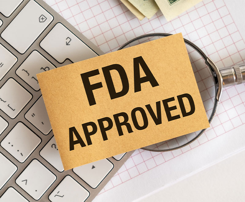 Photo of a computer keyboard, magnifying glass and "FDA Approved" sign
