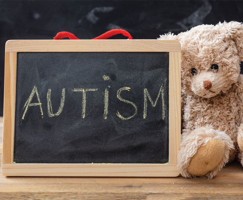 Photo of a teddy bear and chalkboard that says "Autism"