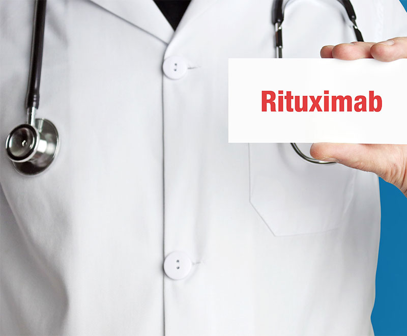 Photo of a healthcare provider holding a sign that says "Rituximab."
