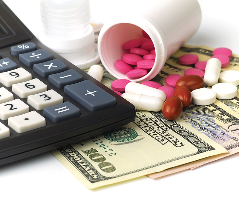 Image of calculator, American dollars and open bottles of pills