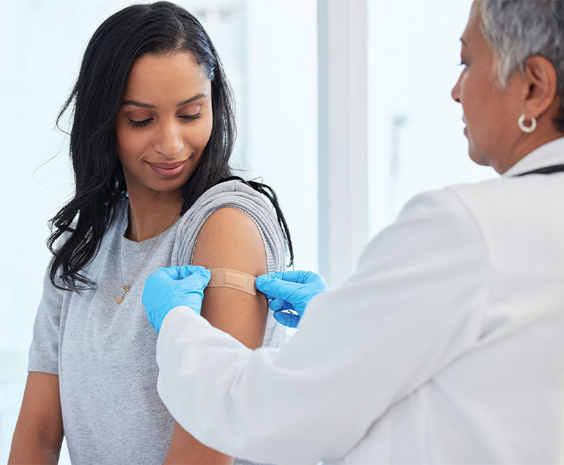 Photo of a healthcare worker putting a bandage on an adult female patient