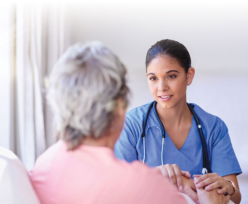 Photo of a healthcare worker speaking with an elderly female patient