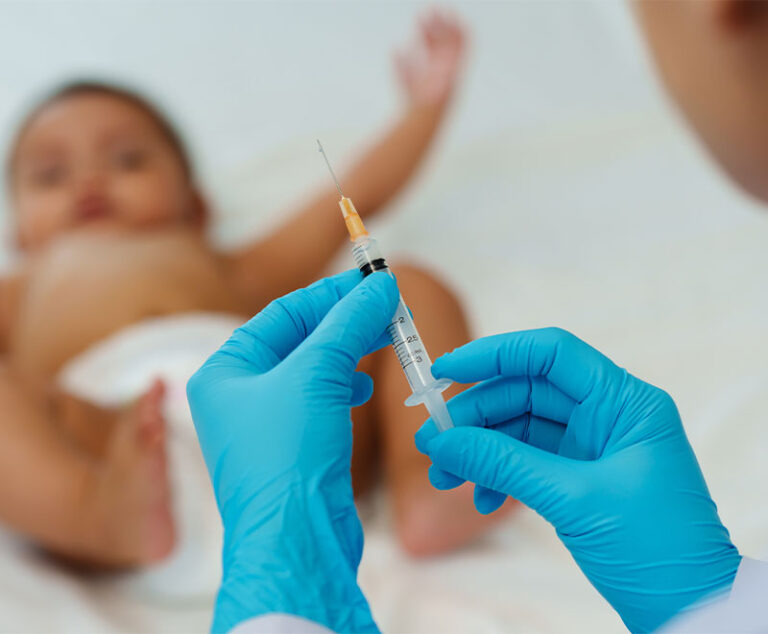 Photo of a syringe prepping to vaccinate a baby
