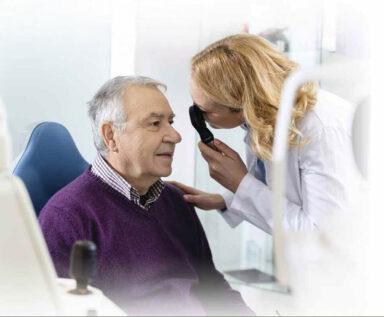 Photo of a senior male patient receiving an eye exam from a female doctor