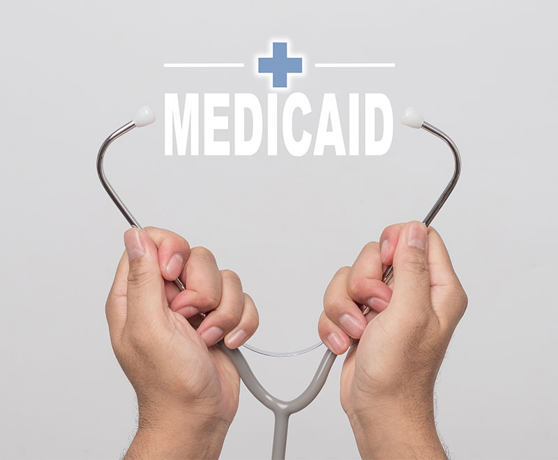 Image of hands holding stethoscope with text "medicaid" between ear pieces