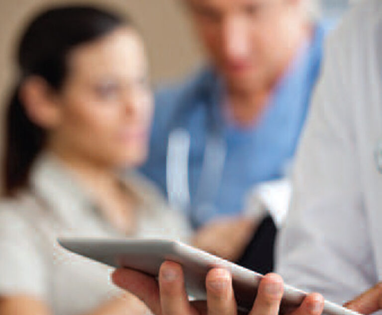 picture of a doctor holding a tablet with coworkers in the background