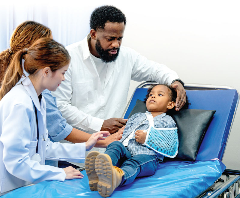 Parents comfort a child lying on a medical table.