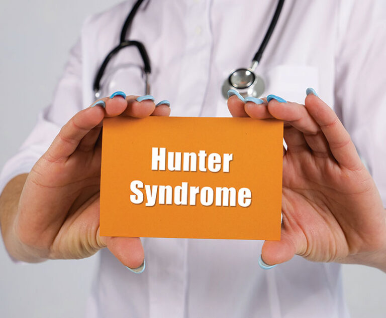 Medical practitioner in a stethoscope holding an orange card with the phrase "Hunter Syndrome" written in white.