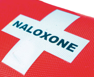 White cross with the word "NALOXONE" across the middle against a red background.